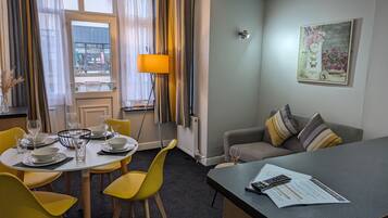 Una camera d'albergo con zona pranzo, divano e scrivania.