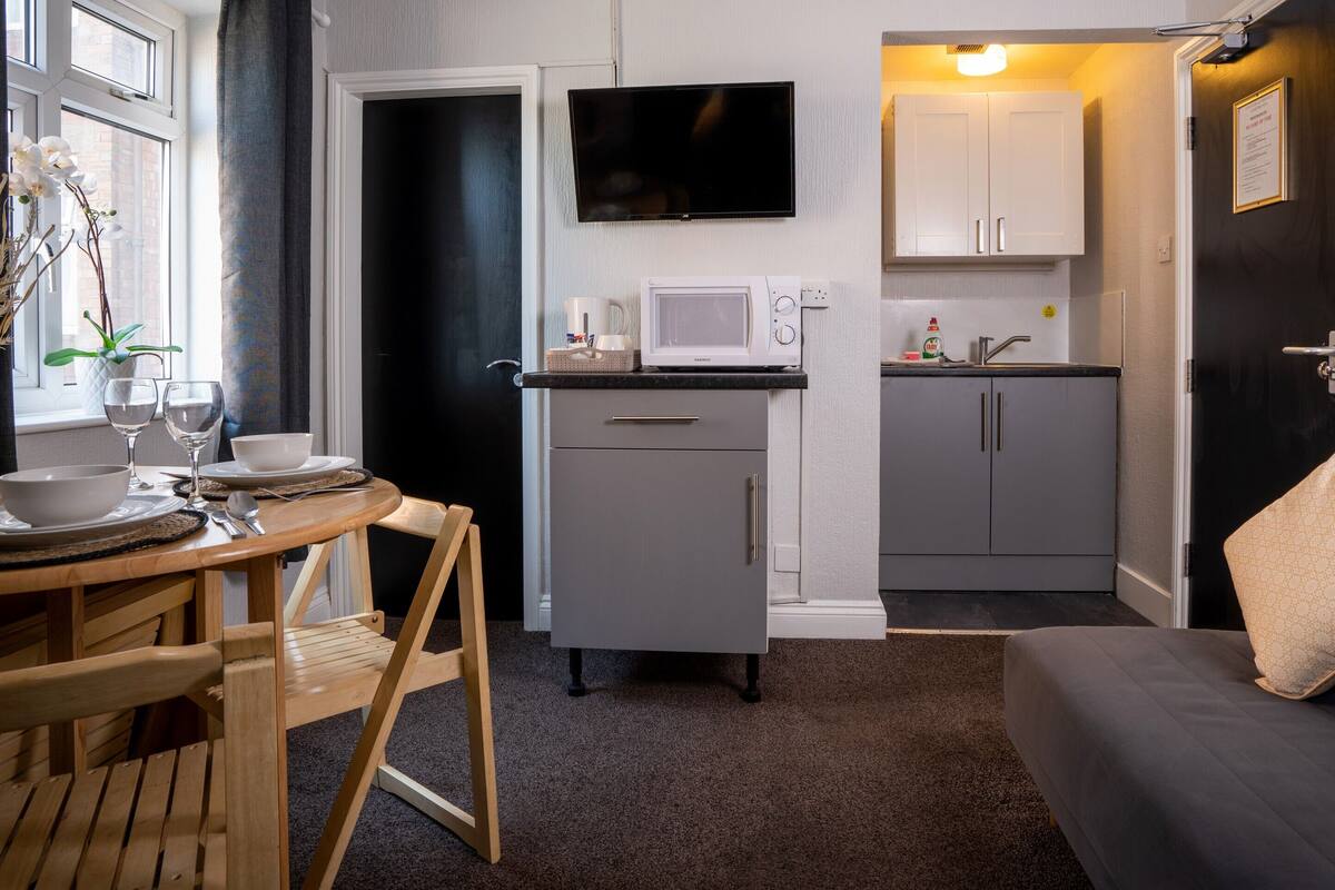 A compact living space with a dining area, kitchenette, and a sofa.