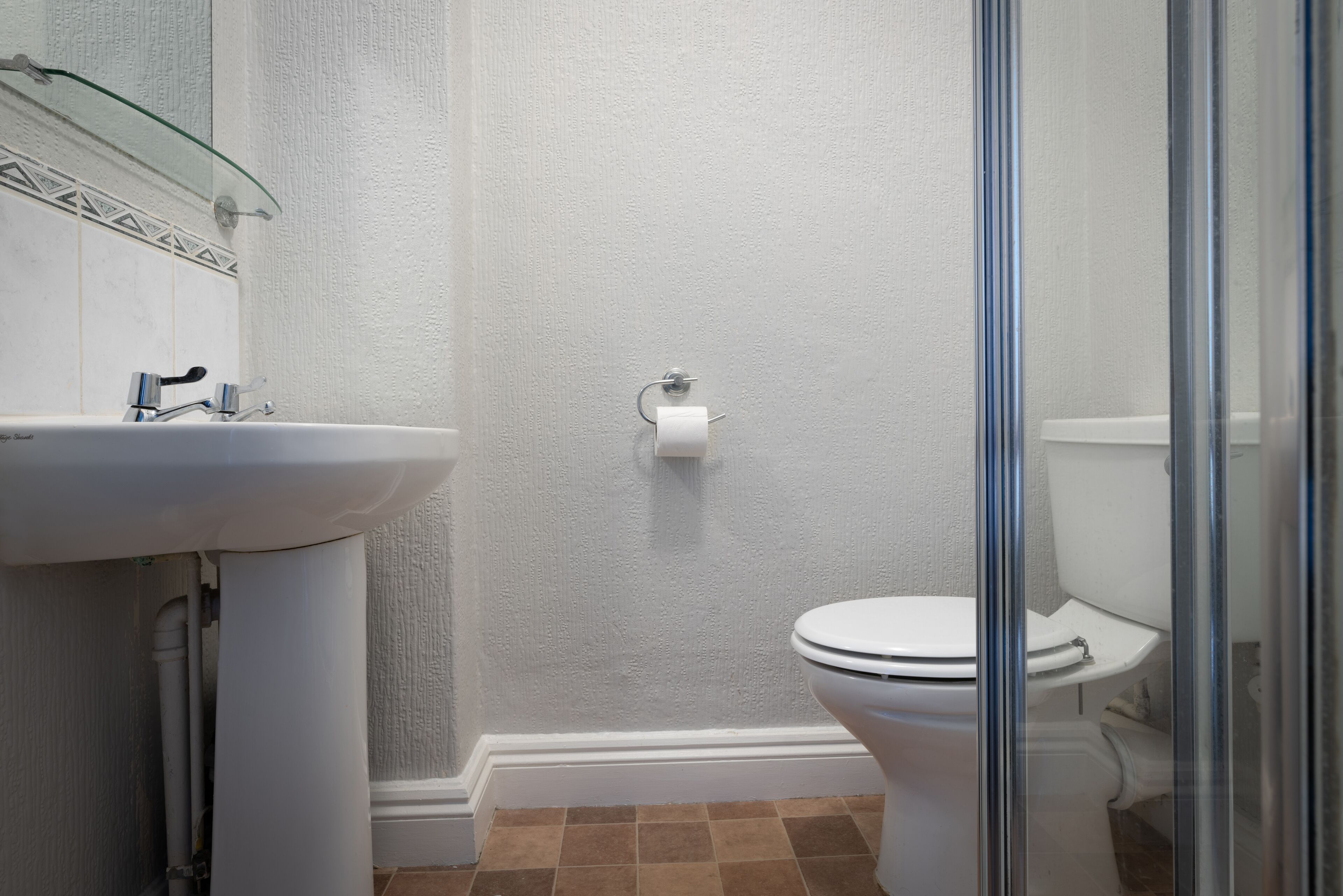 A bathroom with a white sink, toilet, and shower area.