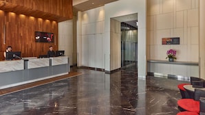Un área de recepción moderna con un mostrador de madera, piso de mármol y una lámpara decorativa grande.