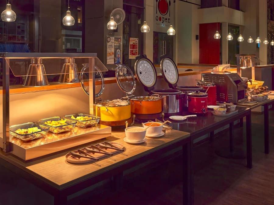 A buffet setup with various food items and serving utensils.