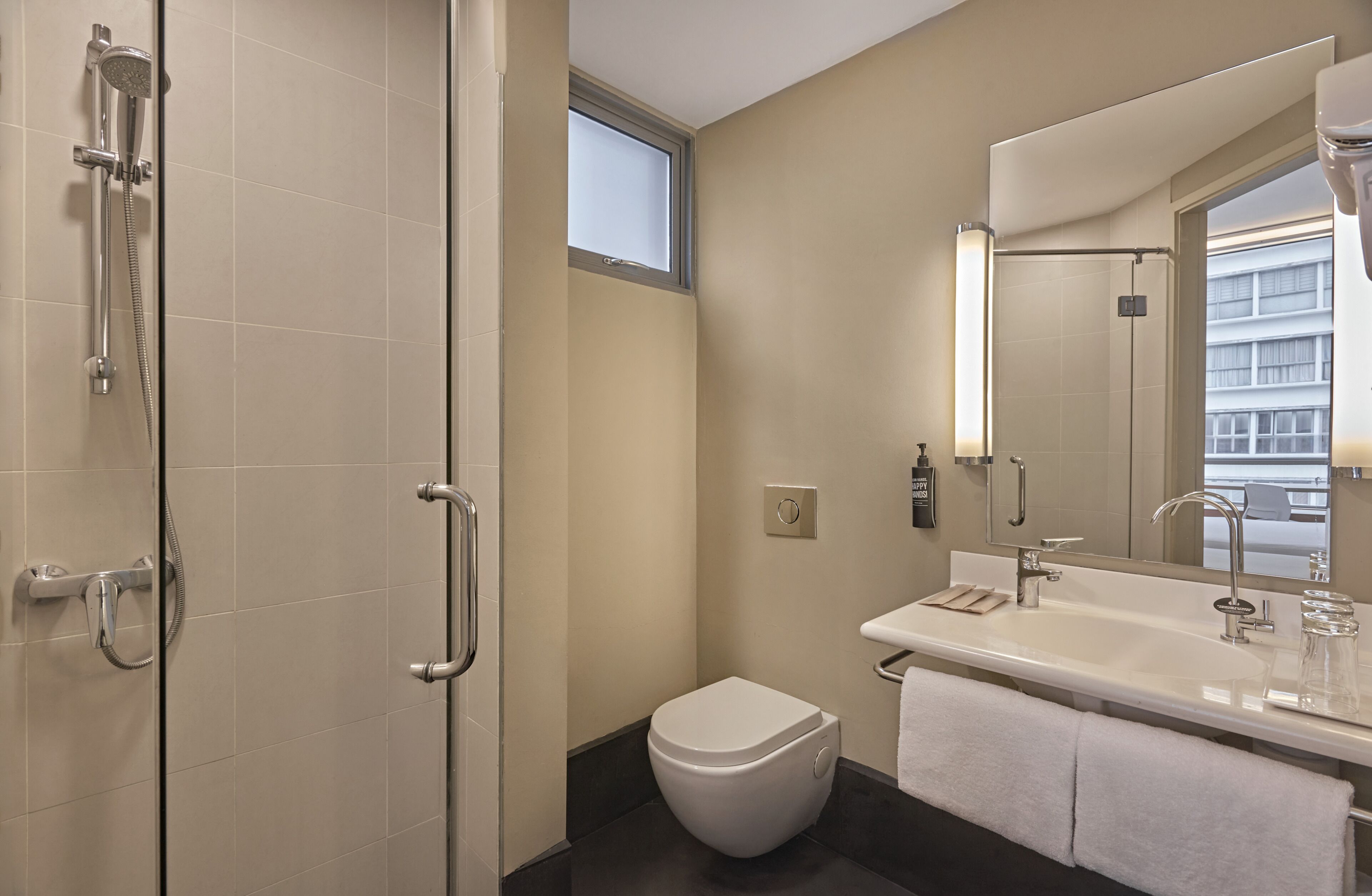A modern bathroom with a shower, toilet, sink, and large mirror.