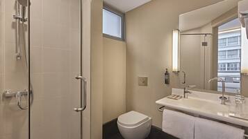 A modern bathroom with a shower, toilet, sink, and large mirror.