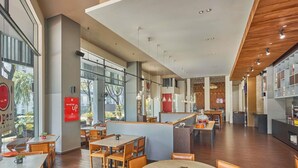 Een ruim restaurant met hoge plafonds, houten vloeren en grote ramen met uitzicht op de omgeving.