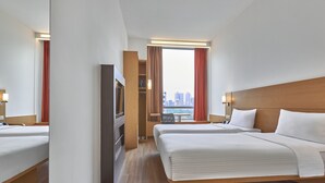 Hotelkamer met twee bedden, een televisie, een bureau en uitzicht op de stad.