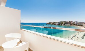 A balcony with a clear view of a beach, boats, and buildings.