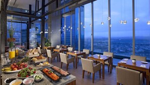 Un comedor con bufé, sillas y vista a la ciudad al anochecer.