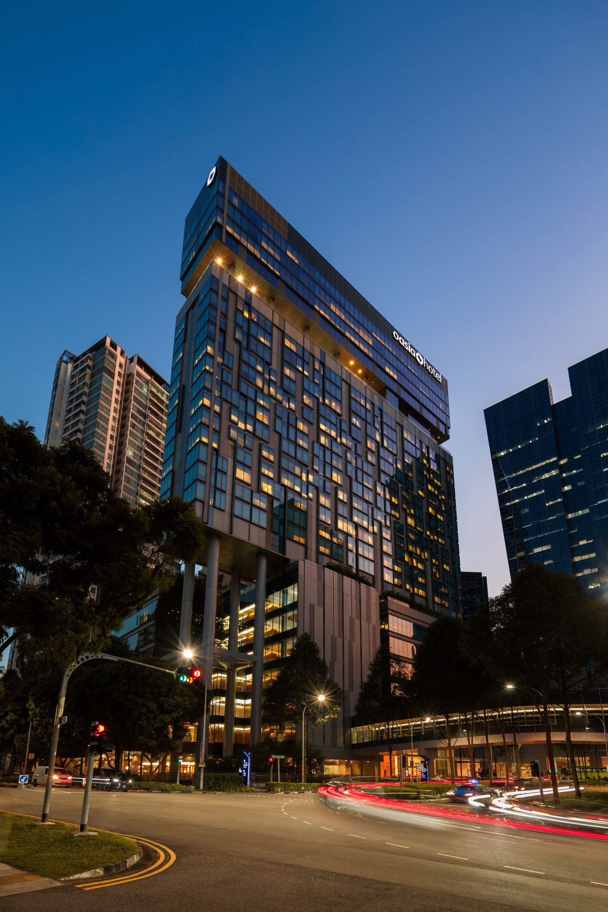 A modern hotel building with multiple floors, large windows, and a prominent signage.