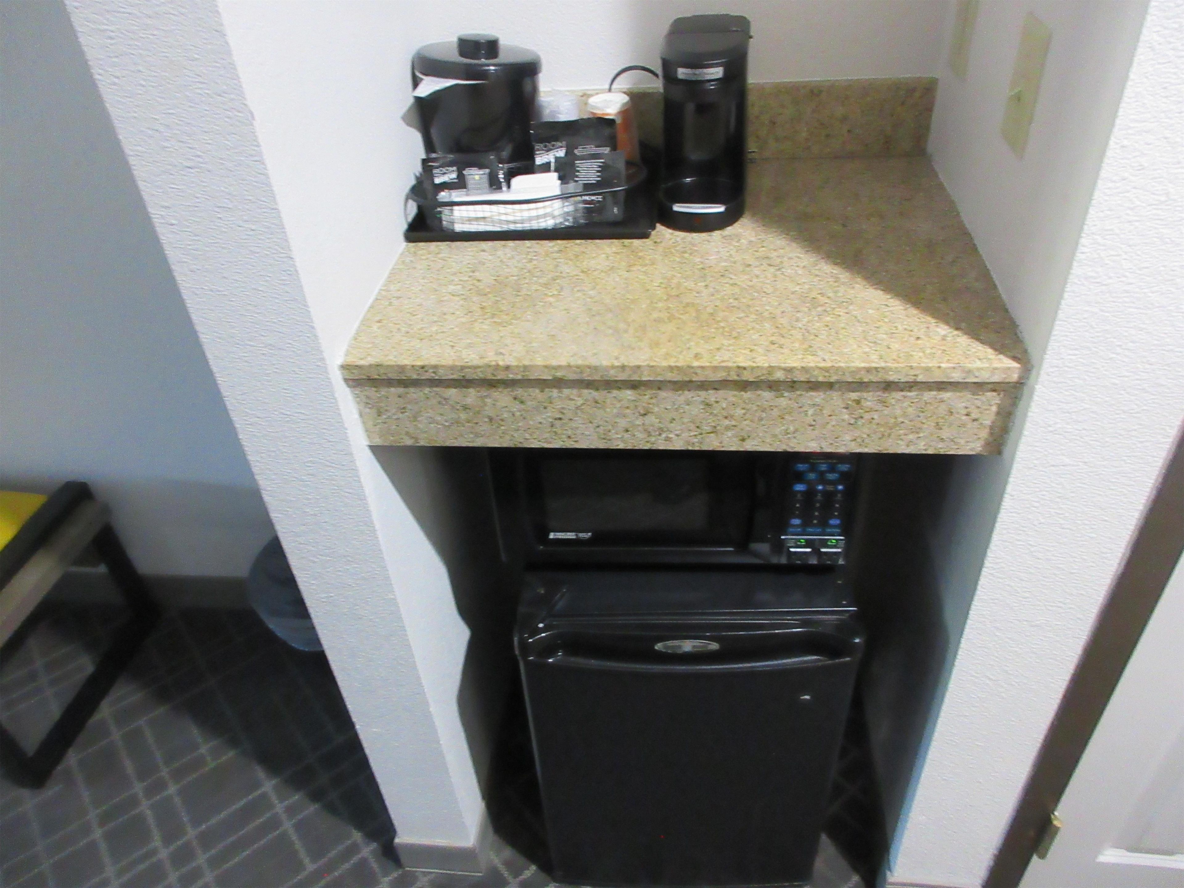 Una kitchenette equipada con cafetera, jarra de café y refrigerador.