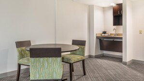 A small, modern room with a round table and four chairs, a kitchenette with a sink and countertop, and a patterned floor. - Comfort Inn & Suites Frisco East - McKinney (Frisco)