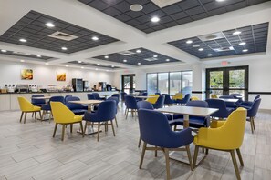 A spacious dining area with high ceilings, multiple tables and chairs, and a kitchen area in the background. - Best Western Plus Frisco East - McKinney (Frisco)