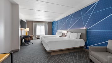 Habitación de hotel con una cama grande, un escritorio con silla, televisor y una pared azul de acento.