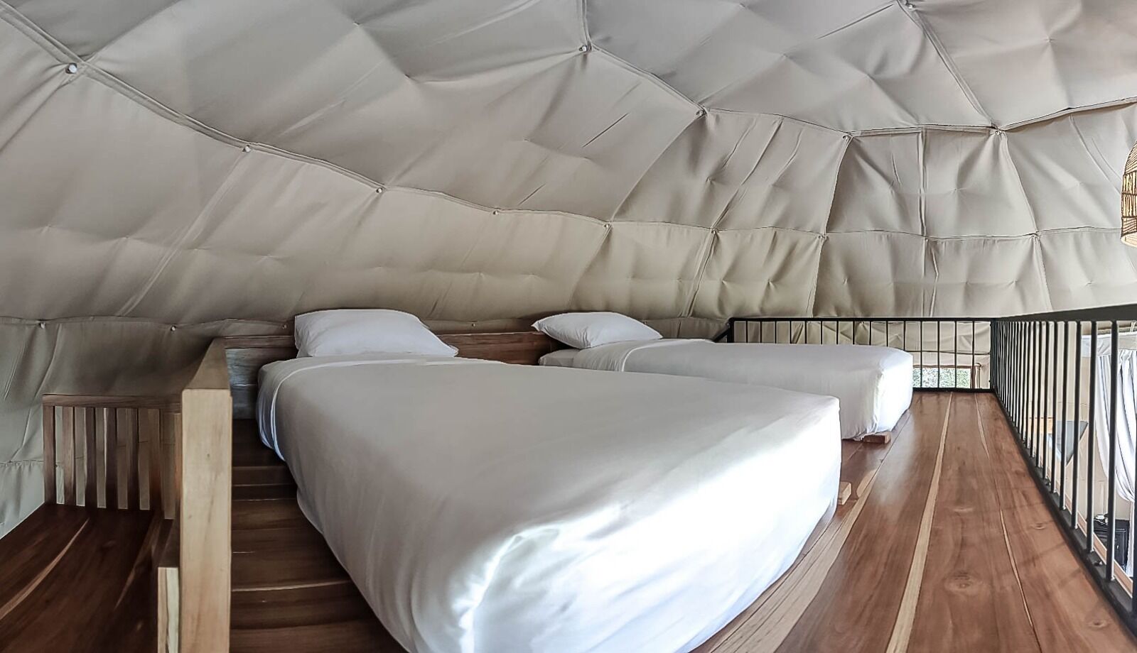 Ein gemütliches, modernes Schlafzimmer im Zeltstil mit zwei Betten und Holzboden.