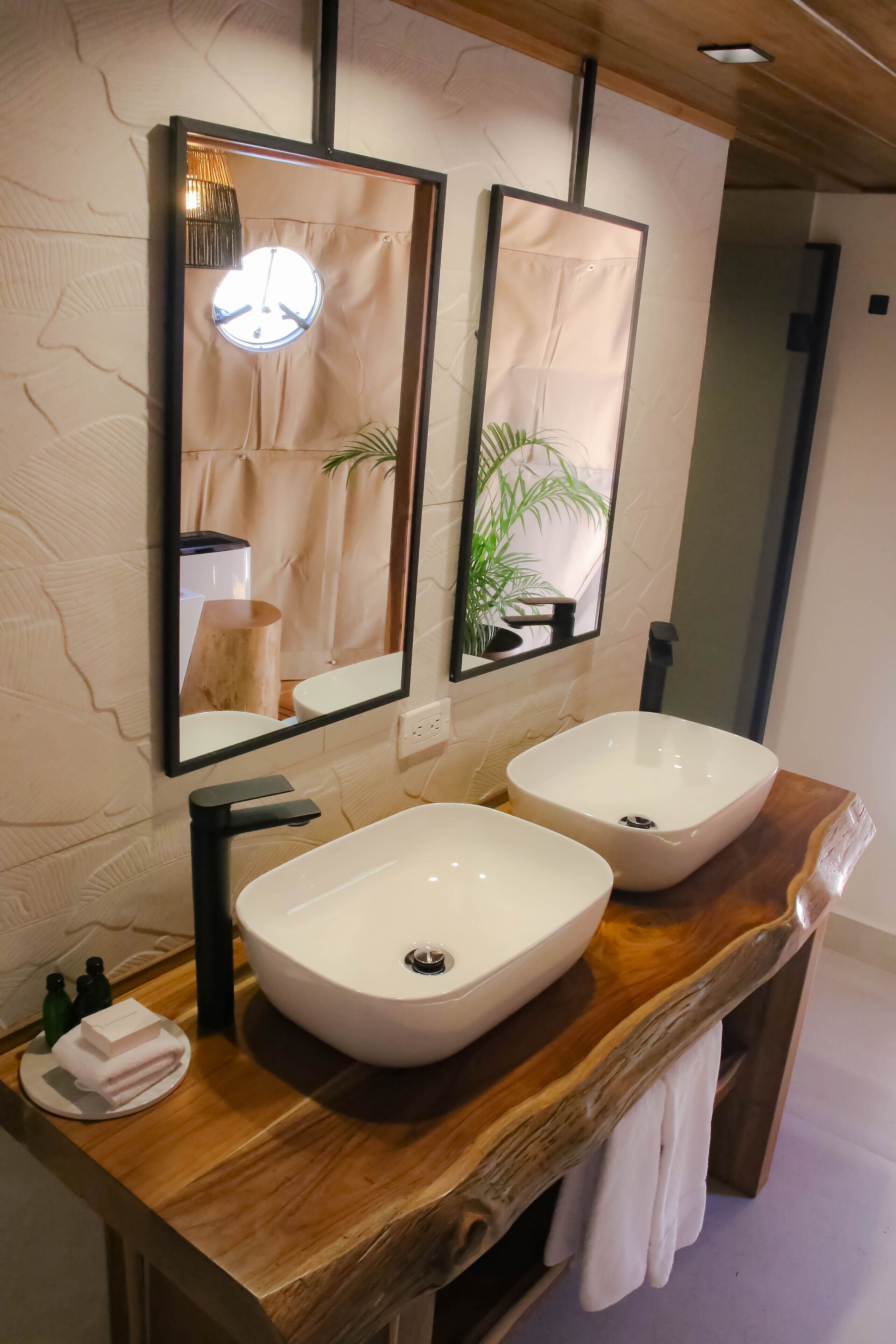 Un baño con dos lavamanos sobre encimera, un mueble de tocador de madera y un espejo con luz.