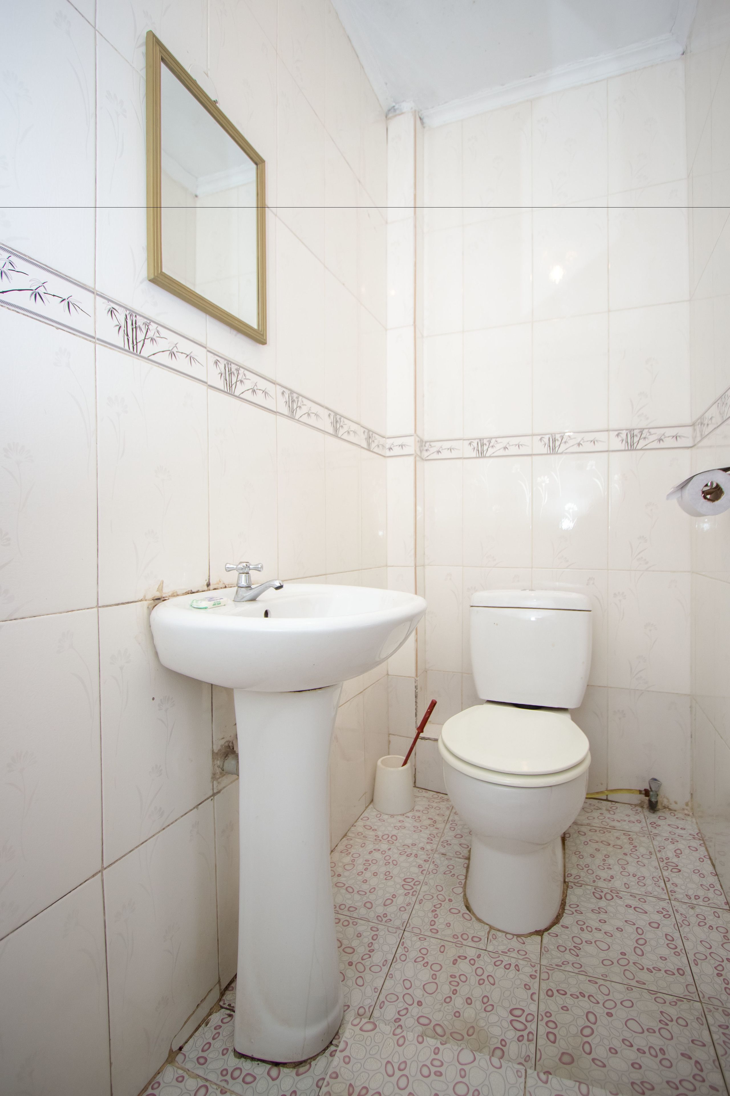A bathroom with a white sink, toilet, and a mirror on the wall.