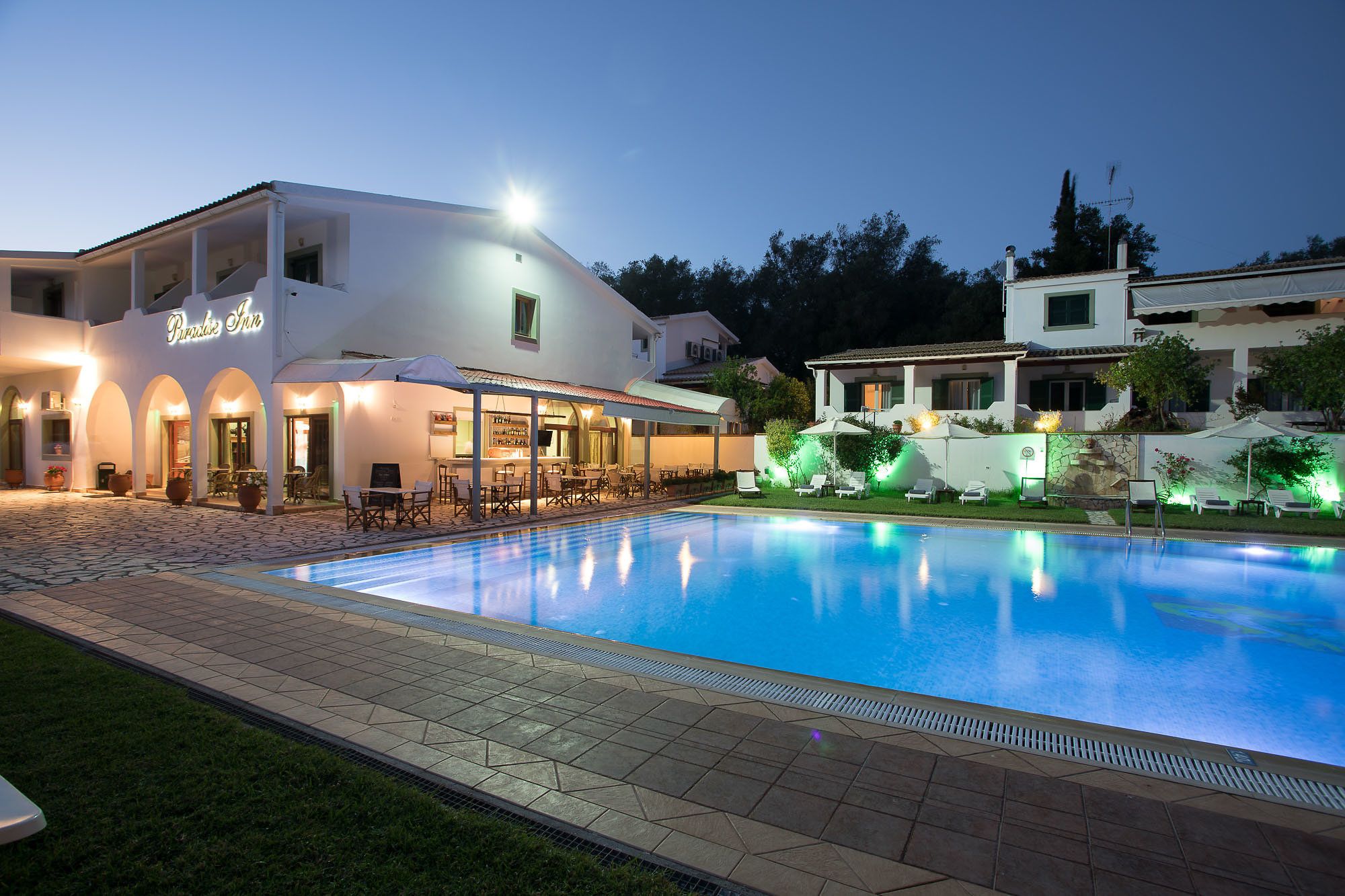 Hotel con piscina, asientos al aire libre y entrada bien iluminada.