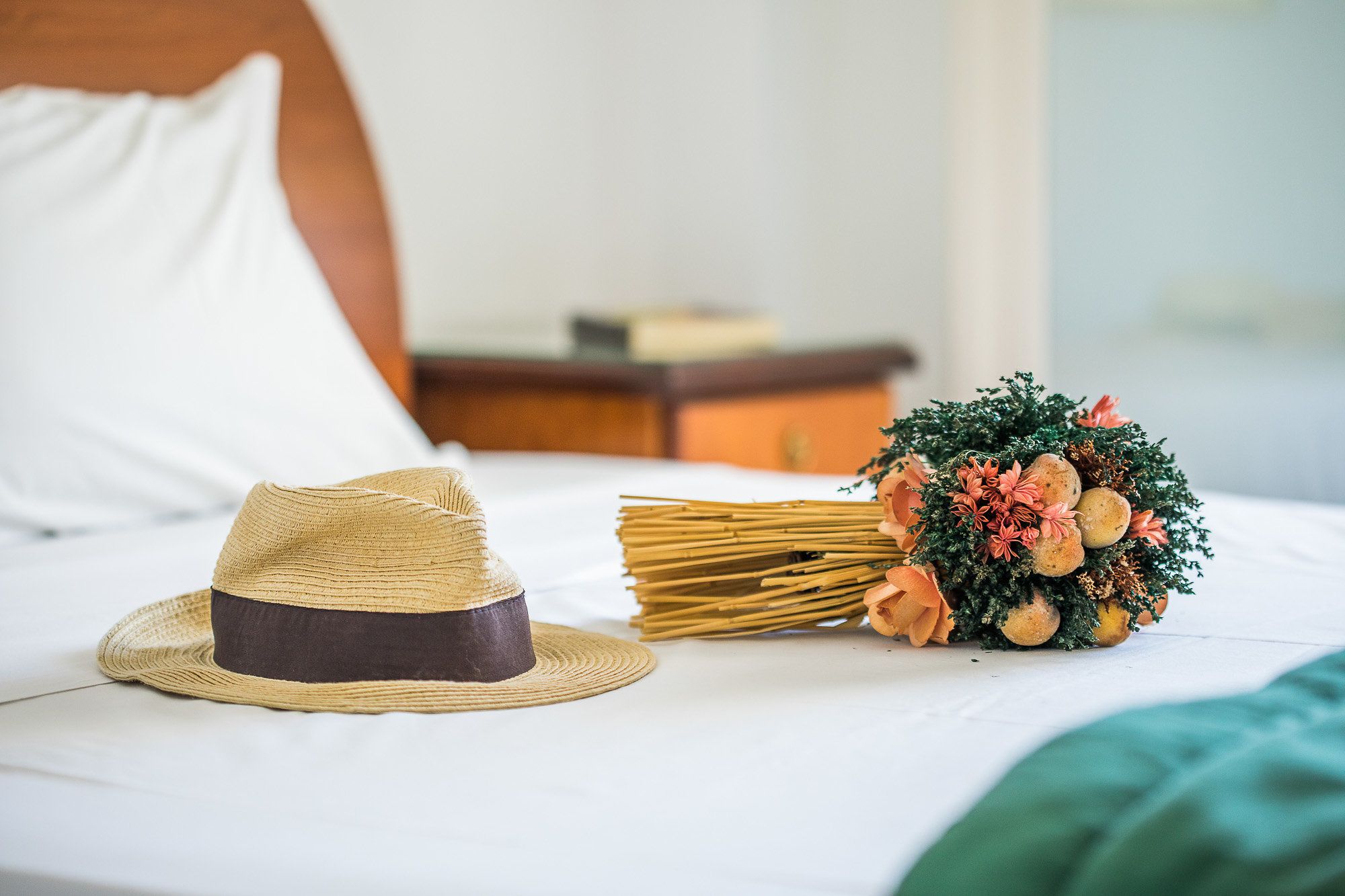 A bed with a straw hat and a bouquet of flowers on it.