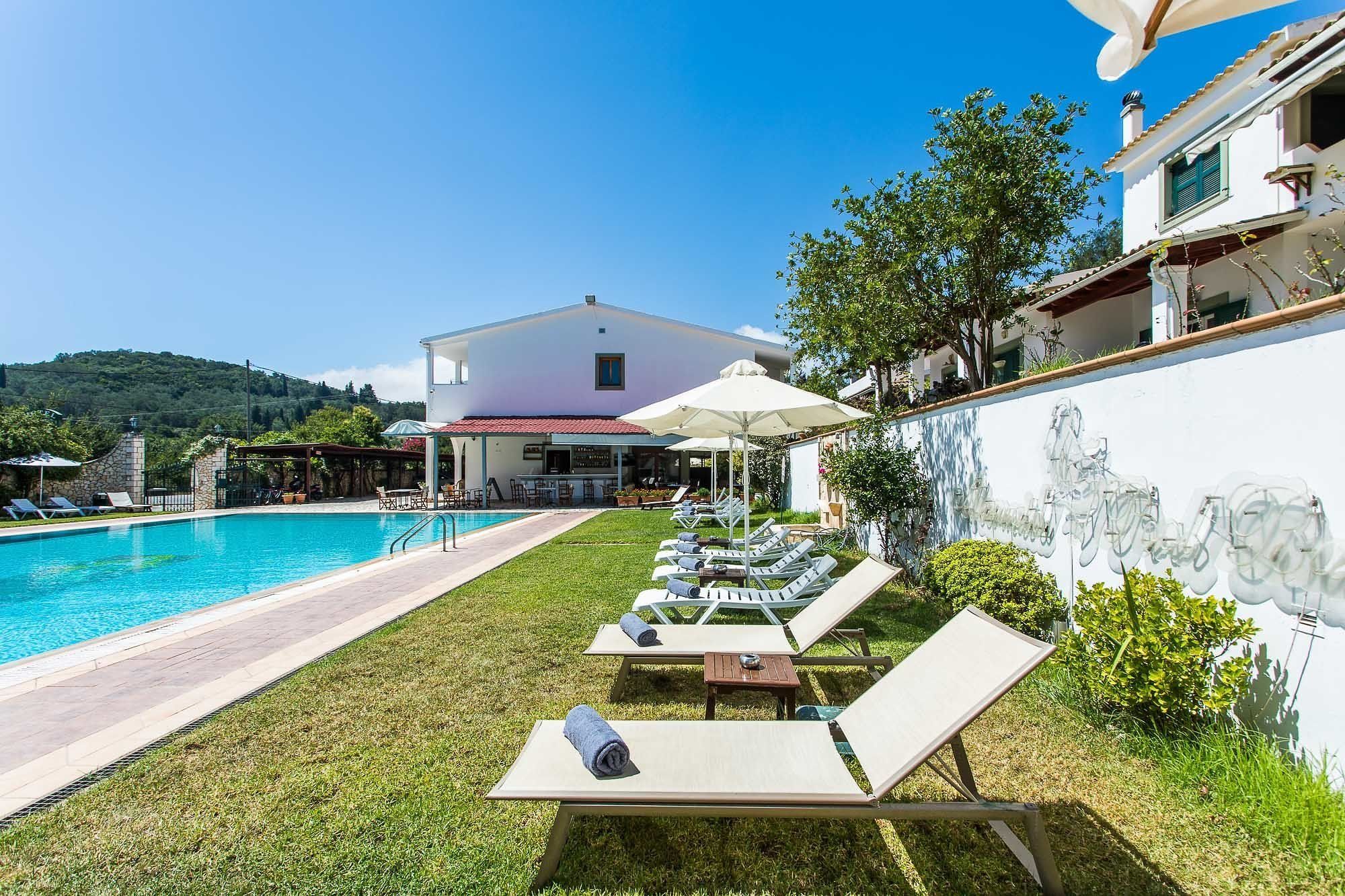 A poolside area with lounge chairs and umbrellas, a pool, and a building in the background.