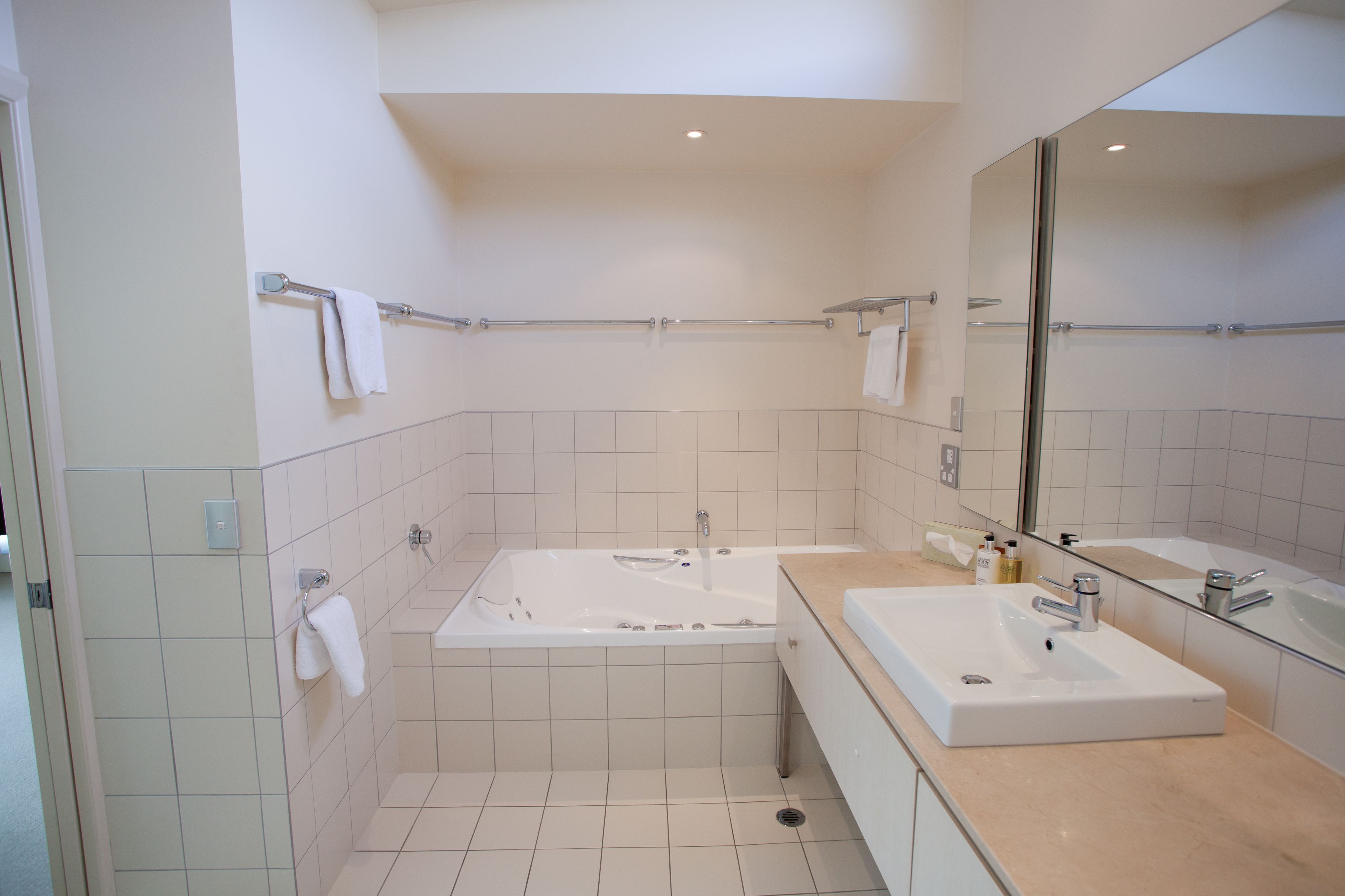 A modern bathroom with a large bathtub, a separate sink, and a mirror.