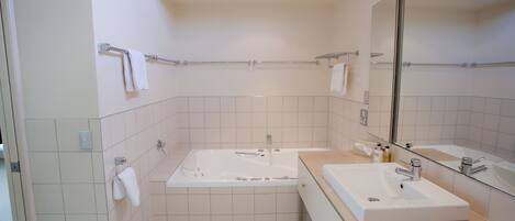 A modern bathroom with a large bathtub, a separate sink, and a mirror.