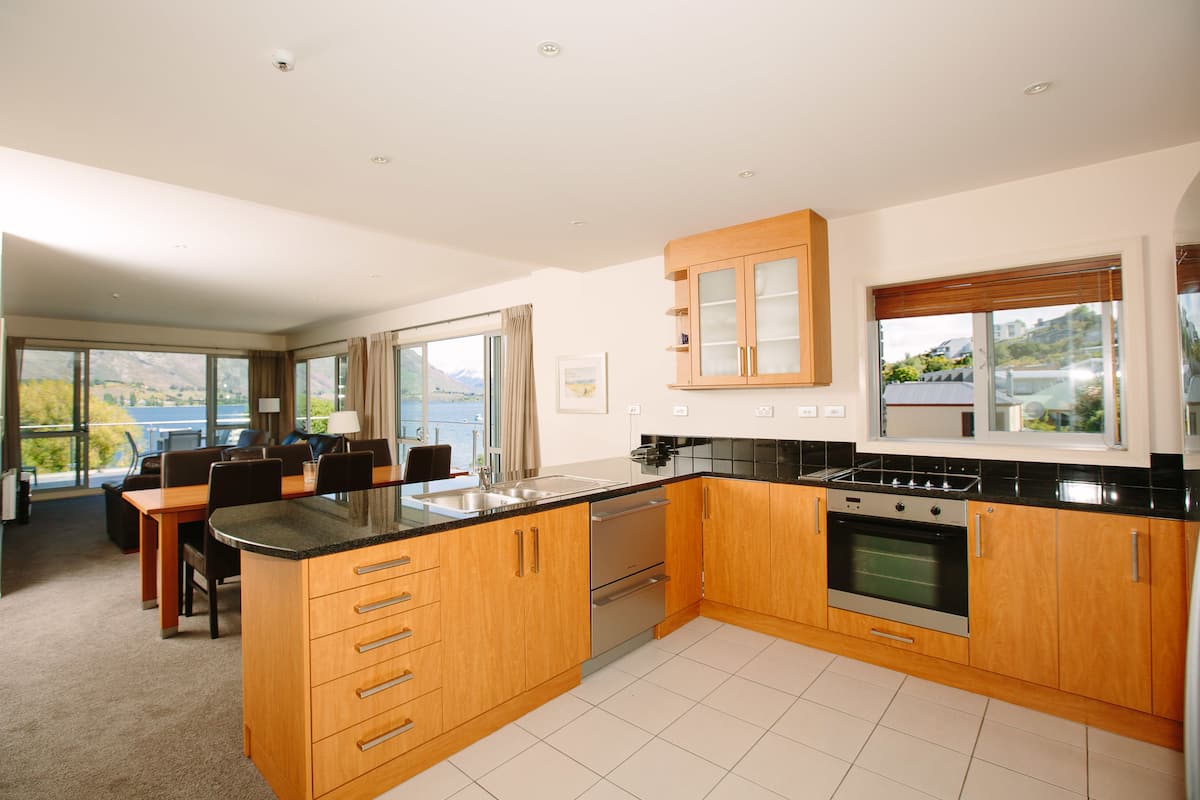 A modern kitchen with wooden cabinets, a black countertop, and stainless steel appliances.