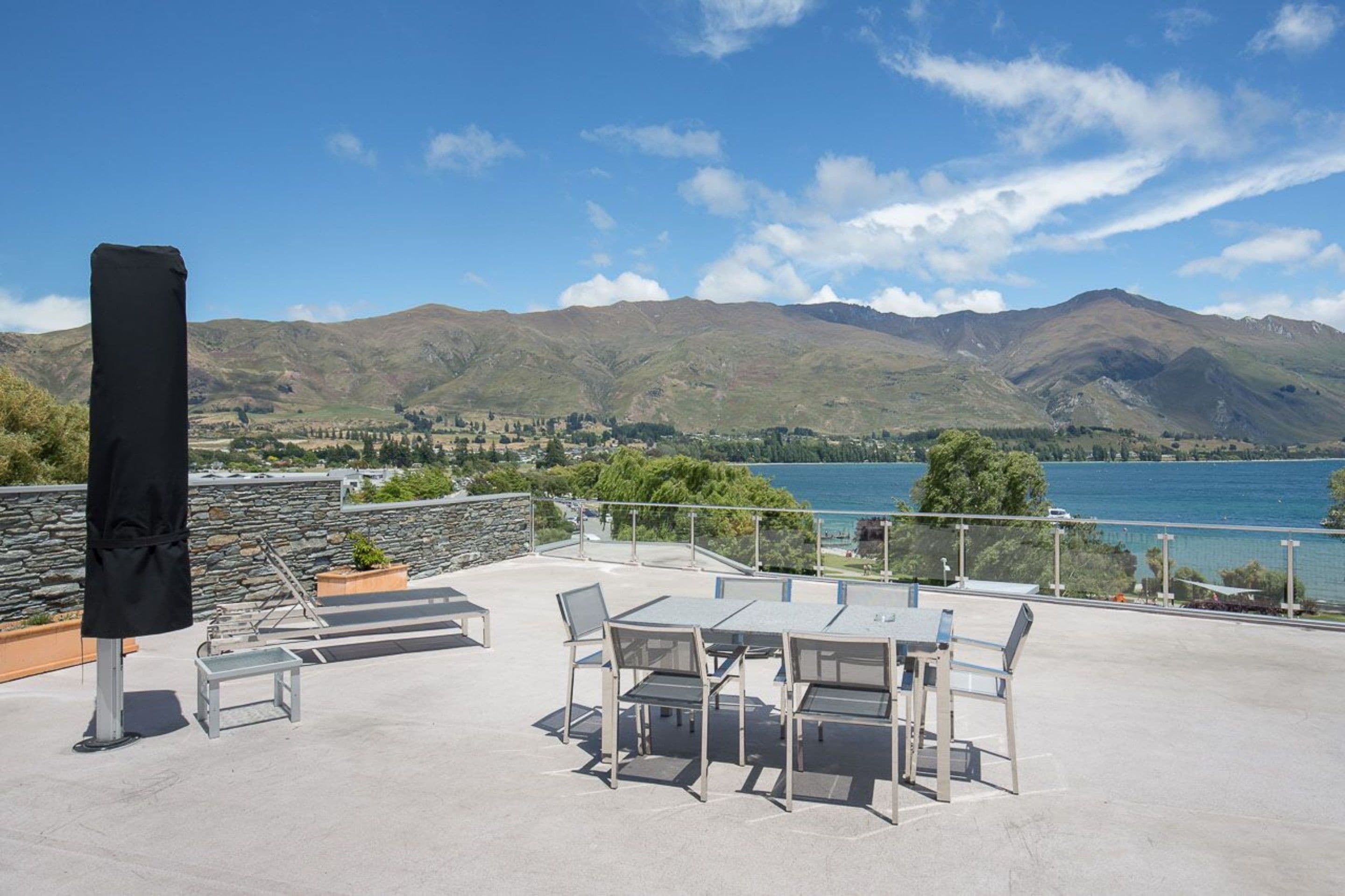Una terraza con mobiliario exterior y vistas a montañas y un lago.