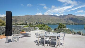 Una terraza con mobiliario exterior y vistas a montañas y un lago.