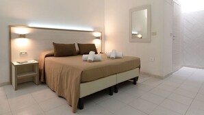 Un dormitorio ordenado con una cama, mesitas de noche, un espejo y una puerta.