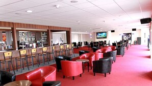 A bar area with red and black chairs, a counter with a bartender, and a television screen. - Southport Holiday Park (Southport)