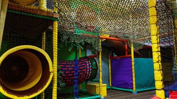 An indoor play area with a netted climbing structure, a tunnel, and various play elements.