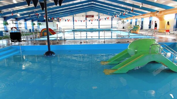 An indoor swimming pool with a green slide and a water slide. - Southport Holiday Park (Southport)