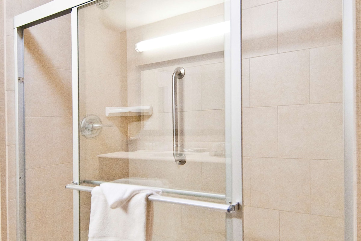 A glass-enclosed shower stall with a white towel hanging on a rack.