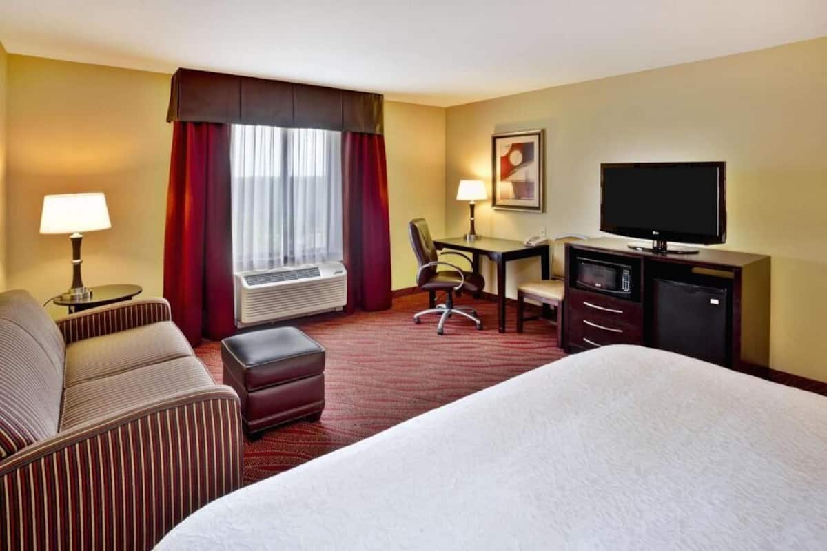 Une chambre d’hôtel équipée d’un lit, d’un bureau, d’une chaise, d’une télévision et d’une lampe.