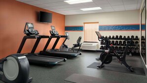 Une salle de sport équipée de tapis de course, d’un vélo elliptique, d’un vélo d’appartement et d’un mur rempli d’haltères.