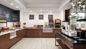 Une cuisine moderne équipée d’un bar pour prendre le petit-déjeuner, de machines à café et de divers produits alimentaires.