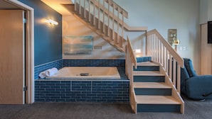 A room with a wooden staircase, a bathtub, and a blue-tiled wall. - Country House Resort (Sister Bay)