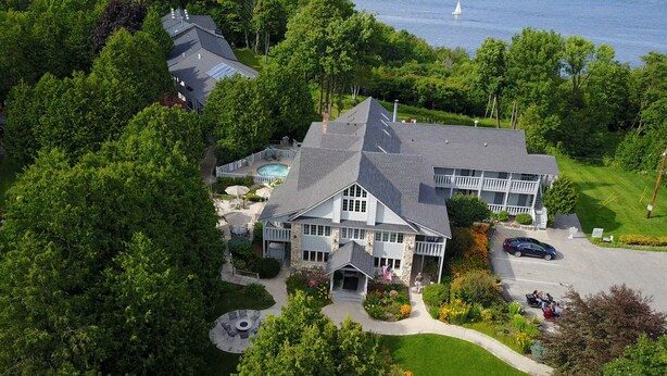 A large, multi-story house with a prominent roof, a swimming pool, and a well-maintained garden. - Country House Resort (Sister Bay)