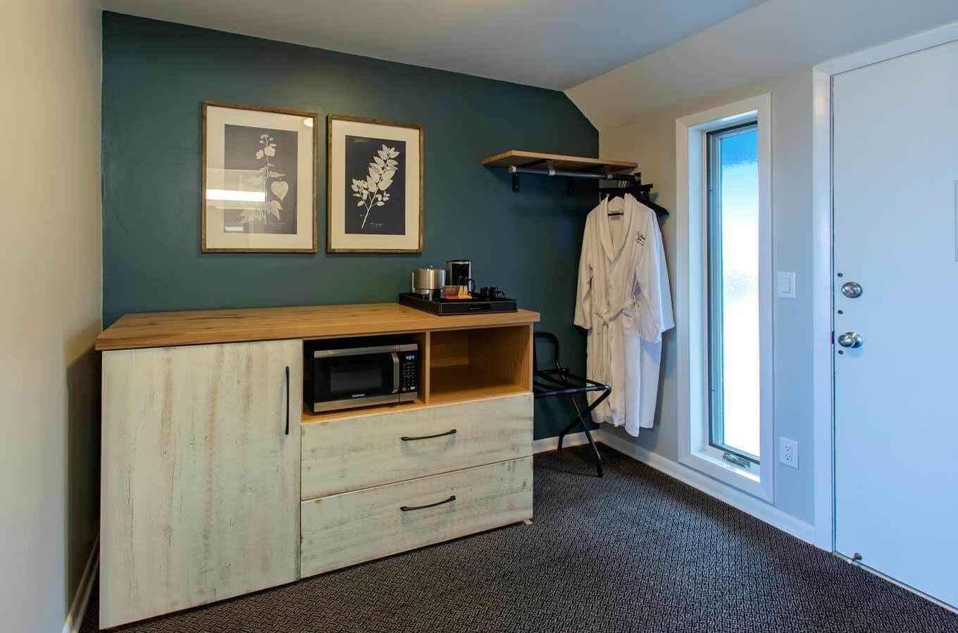 Habitación compacta con kitchenette, perchero y puerta que da a un balcón.