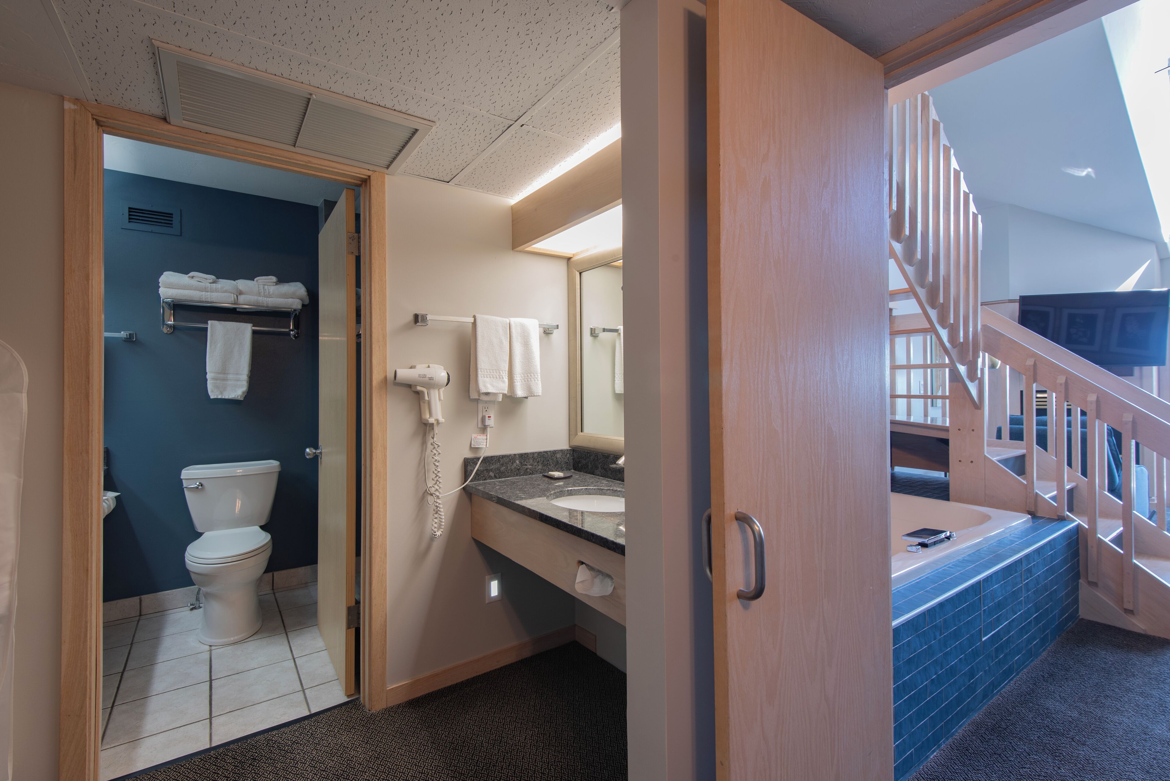 A hotel bathroom with a toilet, sink, and towel rack.