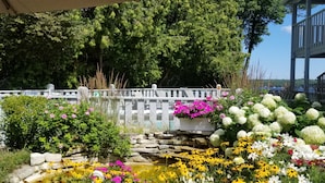 A garden with a pond, various flowers, and a wooden bridge. - Country House Resort (Sister Bay)