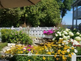 Un jardín con un estanque, diversas flores y un puente de madera.