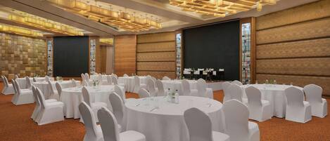 A conference room with round tables, white chairs, and modern lighting fixtures.