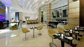 A modern restaurant with a central bar area, multiple dining tables, and contemporary chairs. - Meluha The Fern Mumbai, Powai, Series by Marriott (Mumbai)