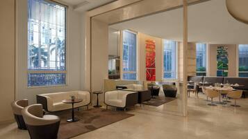 A modern lounge area with seating arrangements, large windows, and decorative elements.