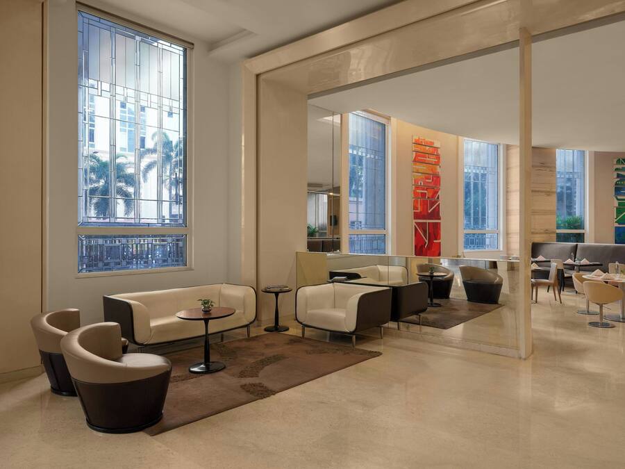 A modern lounge area with seating arrangements, large windows, and decorative elements.
