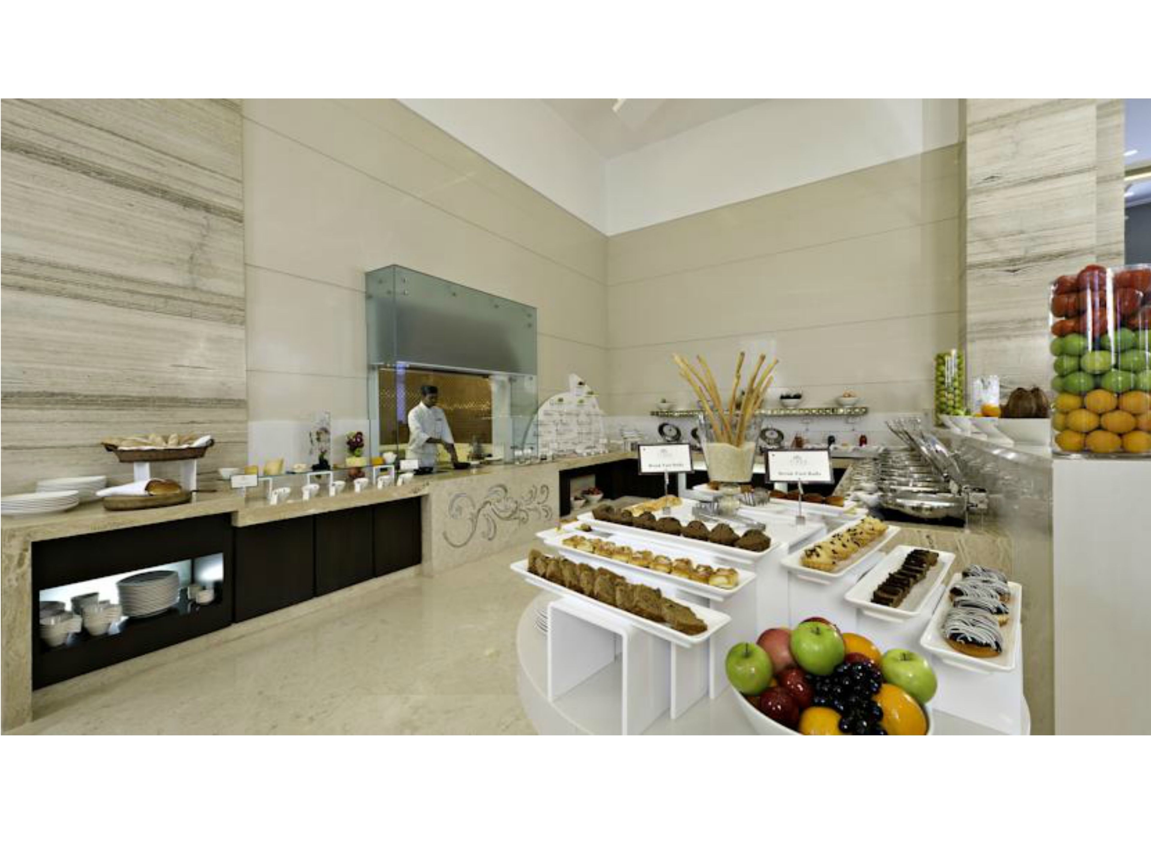 A spacious buffet area with a variety of food items and a chef preparing food.