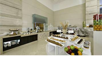A spacious buffet area with a variety of food items and a chef preparing food.