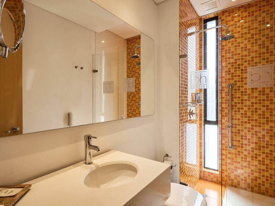 Un baño moderno con un espejo grande, un lavabo y una zona de ducha con puerta de cristal.