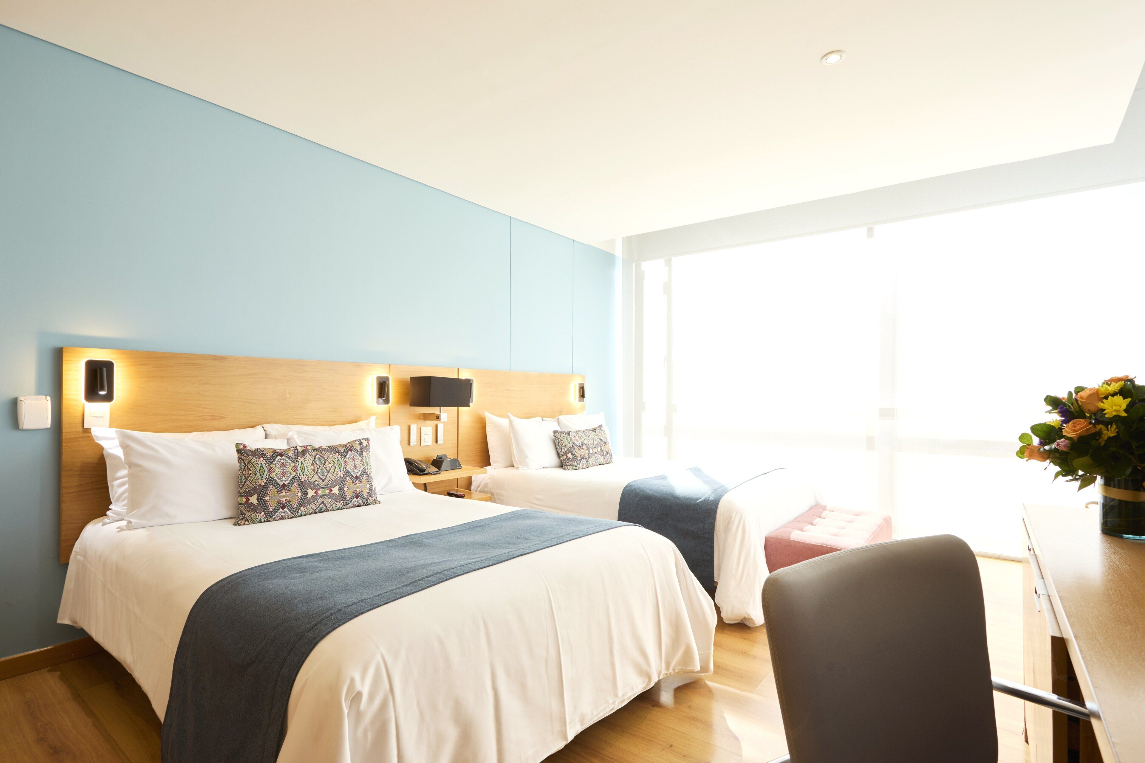 Habitación de hotel con dos camas, un escritorio y una silla.