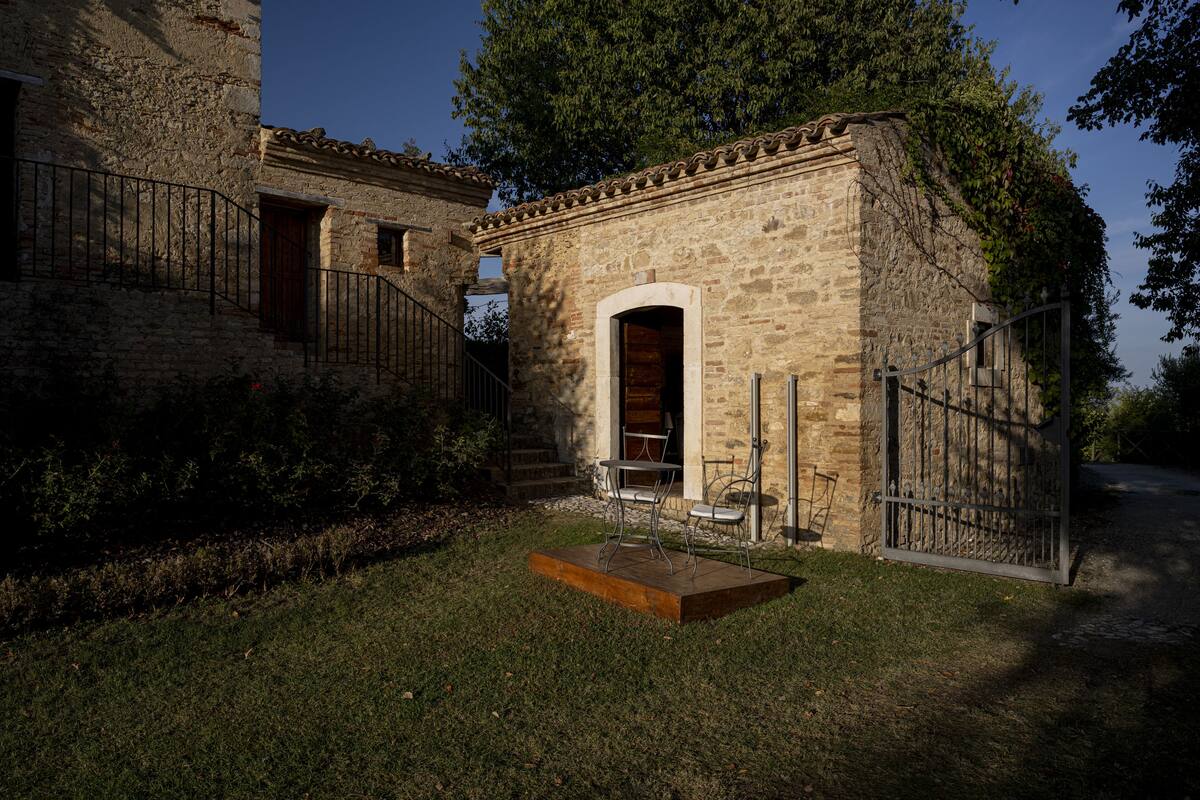 A rustic stone building with a wooden door and a metal gate.